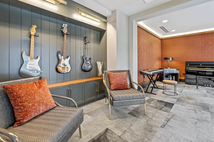 Modern music room with guitars on the wall, two chairs, a keyboard, and a piano in a stylish setting.