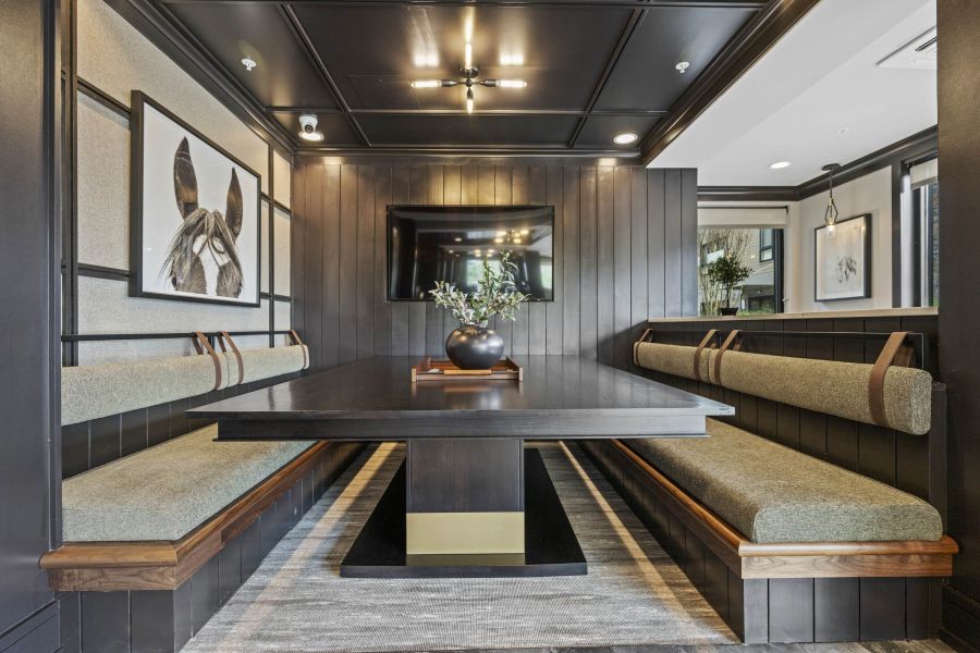Modern dining nook with a dark wood table, bench seating, wall art, and a black vase with greenery.