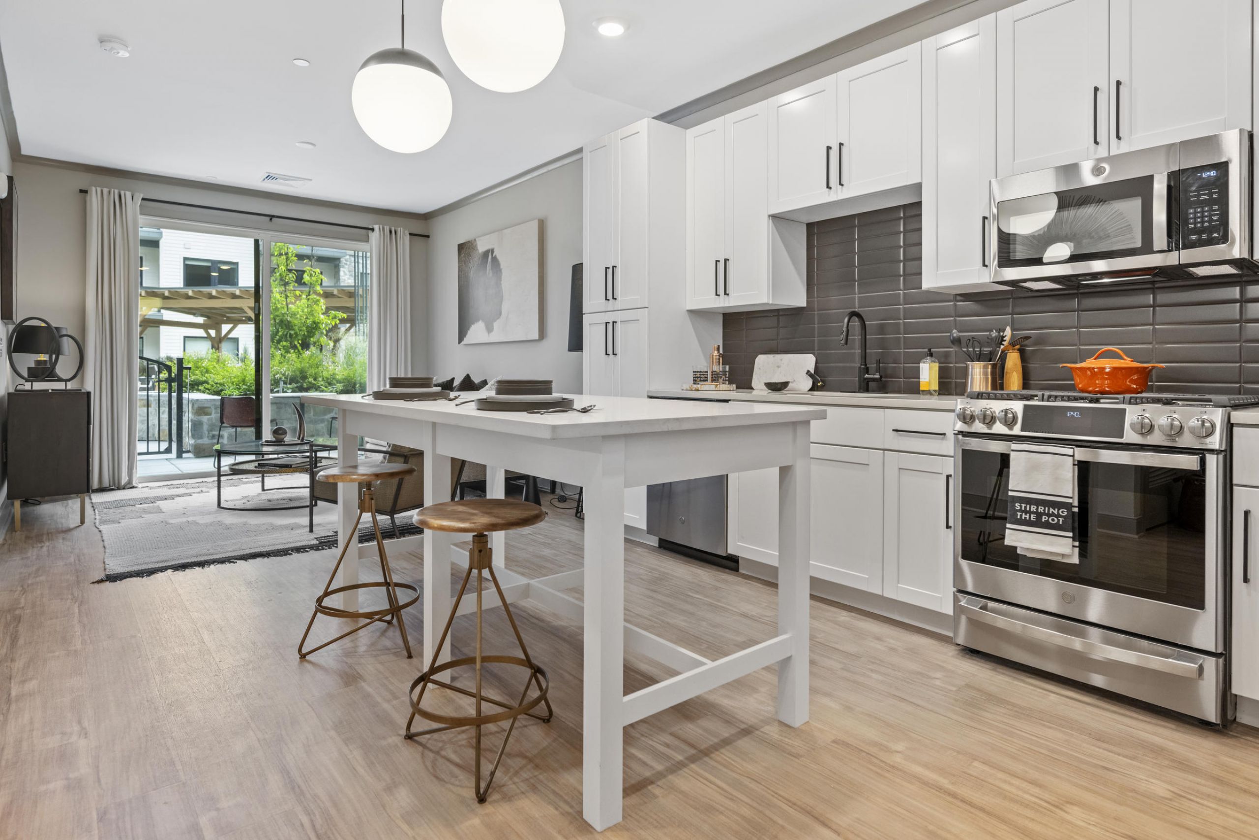 Modern kitchen with white cabinets, island seating, and stainless steel appliances in a bright open-plan space.