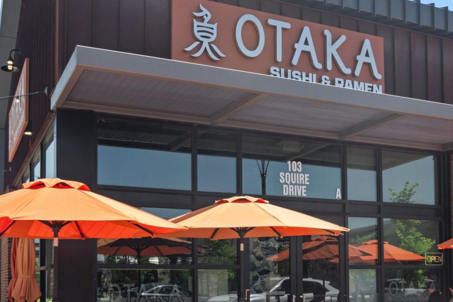 Otaka Sushi & Ramen restaurant exterior with orange umbrellas and patio tables on a sunny day.