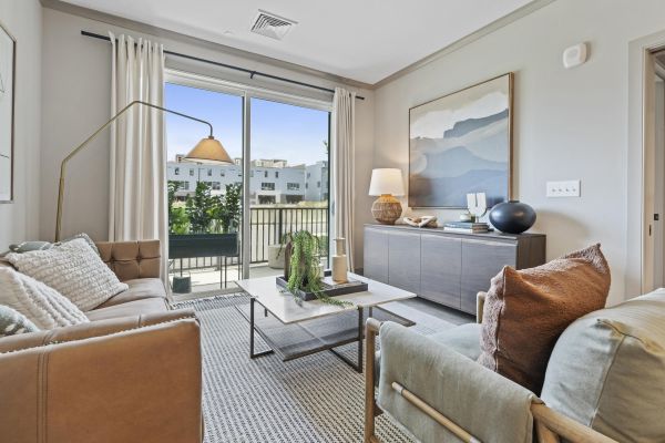 Modern living room with neutral tones, large window, cozy seating, and contemporary decor.